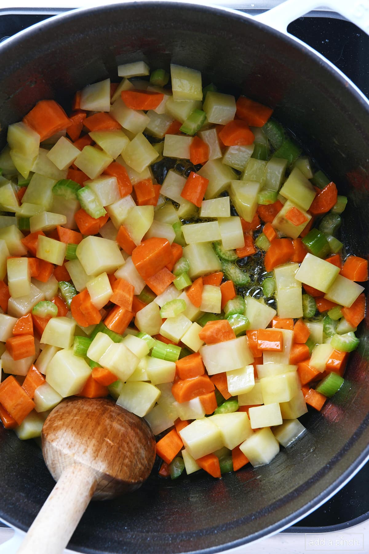 Diced potatoes, carrots, and celery cooking in a Dutch oven.