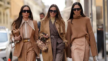 A guest wears sunglasses, earrings, a brown jacket, a brown shirt, a belt, pants, black shoes ; a guest wears a brown trench long coat, a gray jacket ; a guest wears sunglasses, an oversized wool turtleneck woven pullover, a salmon pink skirt, quilted sandals, outside Sportmax, during Milan Fashion Week Fall/Winter 2020-2021 on February 21, 2020 in Milan, Italy.