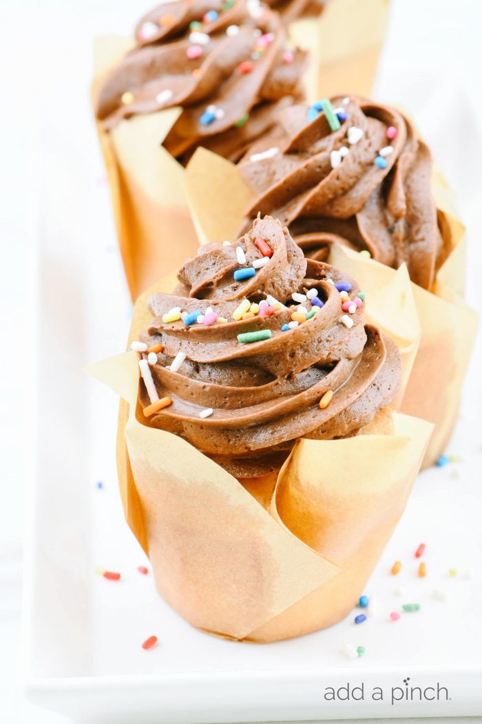 Vanilla cupcakes topped with swirls of chocolate buttercream frosting and sprinkles. 