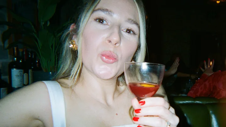 Woman looking at the camera, holding a cocktail.