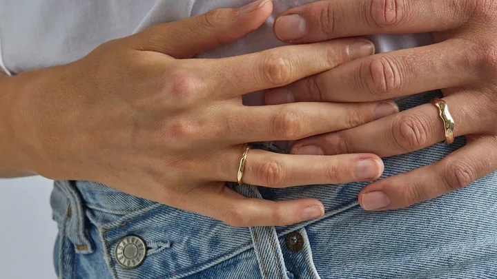 Two hands wearing organic wedding bands