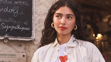 Woman with gold hoop earrings and dark brown, curly hair